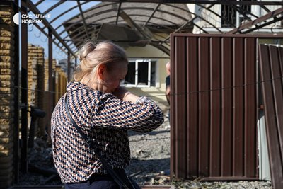 Жанна стоїть біля вʼїзних воріт до свого гаража у селі Мила і чекає, коли поліцейські дозволять забрати тіло її чоловіка, Київщина, 29 серпня 2026 року Жанна стоїть біля вʼїзних воріт до свого гаража у селі Мила і чекає, коли поліцейські дозволять забрати тіло її чоловіка, Київщина, 29 серпня 2026 року