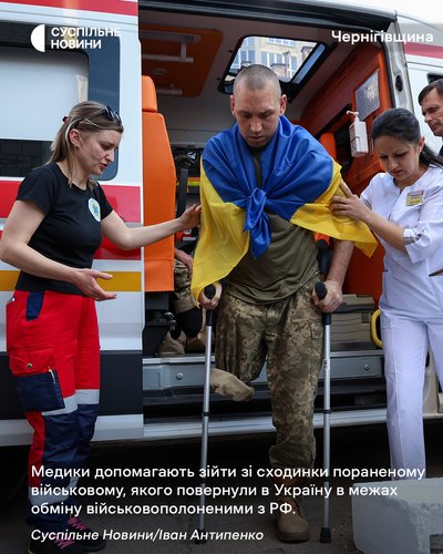 Медики допомагають зійти зі сходинки пораненому військовому в день обміну військовополоненими Медики допомагають зійти зі сходинки пораненому військовому в день обміну військовополоненими