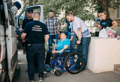 Жінку на кріслі колісному евакуюють Жінку на кріслі колісному евакуюють