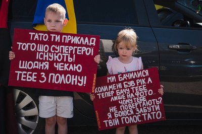 Син та донька подружжя тримали плакати під час однієї з акцій на підтримку свого батька, який був у полоні Син та донька подружжя тримали плакати під час однієї з акцій на підтримку свого батька, який був у полоні