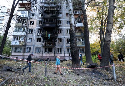Місцеві йдуть повз багатоповерховий будинок, пошкоджений вибухом від удару безпілотника Місцеві йдуть повз багатоповерховий будинок, пошкоджений вибухом від удару безпілотника