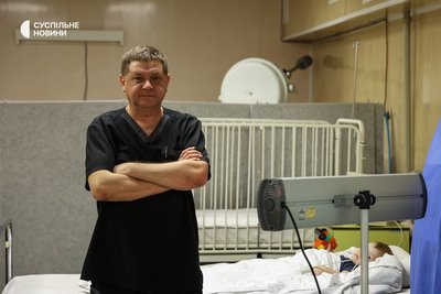 Лікар-анестезіолог херсонської лікарні Олександр стоїть біля ліжка дитини, яка отримала травму стегна через недогляд батьків