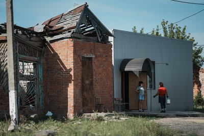 Жінки стоять біля пошкодженого будинку в Граковому Жінки стоять біля пошкодженого будинку в Граковому