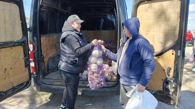 Волонтерка надає гуманітарну допомогу місцевому жителю Волонтерка надає гуманітарну допомогу місцевому жителю