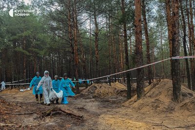 Слідчі виносять мішки з тілами в лісі поблизу Ізюма, де, після звільнення Силами оборони міста, виявили понад 440 могил. Харківщина, 16 вересня 2022 року