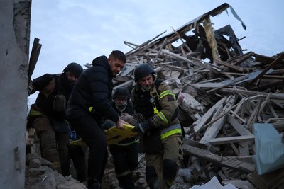 Рятувальники виносять поранену жінку, яку вони діставали з-під завалів у Херсоні