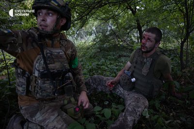 Пораненому військовому з екіпажу ударних дронів надають першу допомогу на узбіччі у Родинському, Донеччина, 18 липня 2025 року Пораненому військовому з екіпажу ударних дронів надають першу допомогу на узбіччі у Родинському, Донеччина, 18 липня 2025 року