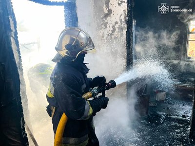 Рятувальник гасить пожежу у приватному будинку Рятувальник гасить пожежу у приватному будинку