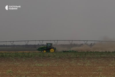 Трактор працює поруч зі зрошувальною системою для поливу полів на Херсонщині, липень 2025 року