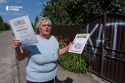Людмила Рябкіна, рідна сестра тещі екскомбрига Лучанова, біля свого будинку показує подяки від військових за те, що вона пече для них коржики. Калинівка, 13 липня 2026 року Людмила Рябкіна, рідна сестра тещі екскомбрига Лучанова, біля свого будинку показує подяки від військових за те, що вона пече для них коржики. Калинівка, 13 липня 2026 року