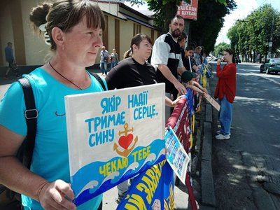 Учасниця акції тримає плакат на підтримку сина, якого чекає Учасниця акції тримає плакат на підтримку сина, якого чекає