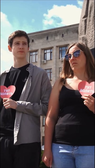 Чоловік і жінка стоять із серцями у руках із надписом "тут болить" Чоловік і жінка стоять із серцями у руках із надписом "тут болить"