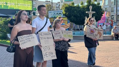 Учасники акції тримають картонки із різними гаслами Учасники акції тримають картонки із різними гаслами