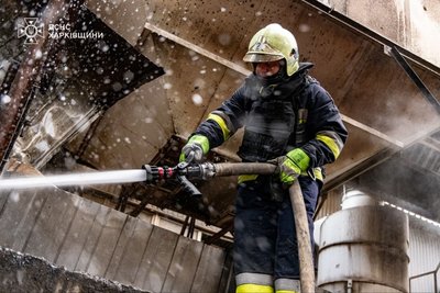 Рятувальник гасить пожежу складу, що виникла після російського удару Рятувальник гасить пожежу складу, що виникла після російського удару