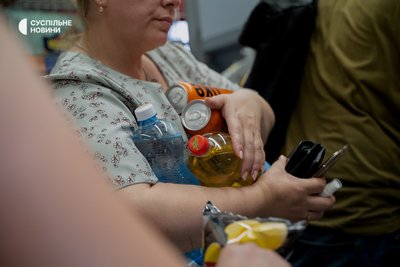 жінка тримає пляшки з водою в черзі у мінімаркеті на Подолі у Києві, 13 липня 2024 року, спека у Києві жінка тримає пляшки з водою в черзі у мінімаркеті на Подолі у Києві, 13 липня 2024 року, спека у Києві