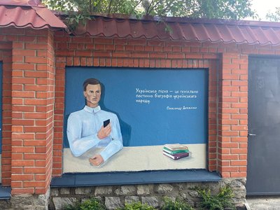 Олександр Довженко зі смартфоном на Літературному муралі в Ірпені Олександр Довженко зі смартфоном на Літературному муралі в Ірпені