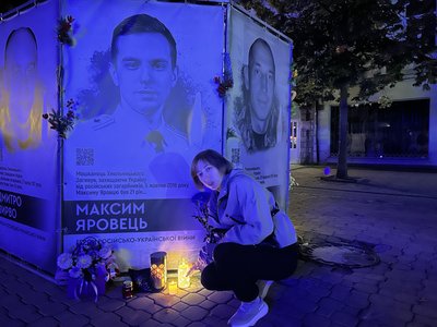 Учасниця акції поставила лампадку біля портрета загиблого військового Учасниця акції поставила лампадку біля портрета загиблого військового