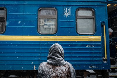 Жінка стоїть під снігом біля евакуаційного потяга у Покровську