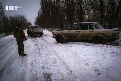 Волонтери допомагають військовим витягти їхній автомобіль, який з'їхав у кювет на околицях Бахмута, лютий 2023 року