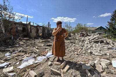 Жінка стоїть біля будинку, зруйнованого внаслідок обстрілу Заоскілля біля Куп'янська