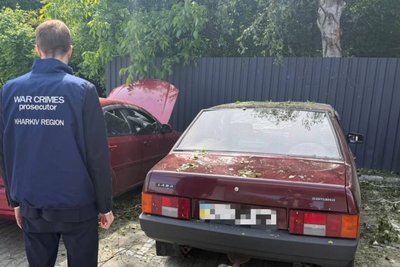 Працівник прокуратури стоїть біля автівок, які були пошкоджені внаслідок влучання російського БпЛА у Немишлянському районі, Харків, 1 червня 2026 року
