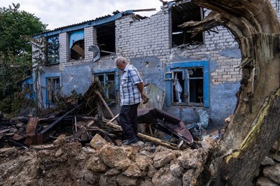 Чоловік стоїть біля пошкодженої через російський обстріл будівлі у Херсоні