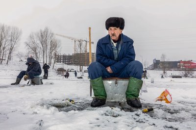 Чоловік ловить рибу в лунці на річці Дніпро у Києві