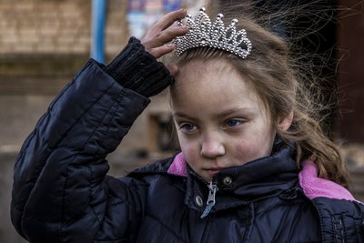 7-річна Аня приміряє срібну діадему принцеси біля свого будинку в одному із міст Донеччини, 25 січня 2023 року. Через постійні обстріли міста Аня з родиною живуть у підвалі будинку. У перерві між обстрілами дівчинка виходить погратись на вулицю. 7-річна Аня приміряє срібну діадему принцеси біля свого будинку в одному із міст Донеччини, 25 січня 2023 року. Через постійні обстріли міста Аня з родиною живуть у підвалі будинку. У перерві між обстрілами дівчинка виходить погратись на вулицю.