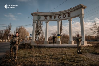 Військові і волонтери фотографуються на фоні стелли на вїзді у Херсон після деокупації міста, 15 листопада 2022 року.
