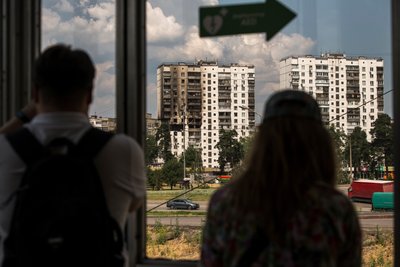 Люди на станції метро дивляться на пошкоджений через вибух газу будинок у Києві