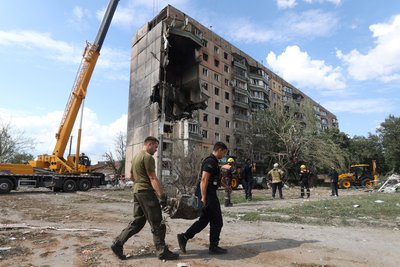 Рятувальники виносять уламок ракети біля обстріляного будинку у Кривому Розі