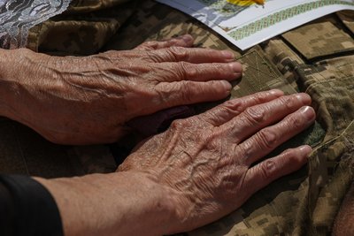 Руки матері на тілі загиблого українського військового під час прощання з ним на Харківщині