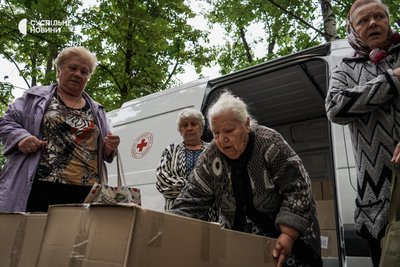Жінки отримують коробки з гуманітарною допомогою, яку волонтери привезли у віддалений мікрорайон на Салтівці у Харкові, липень 2022 року.