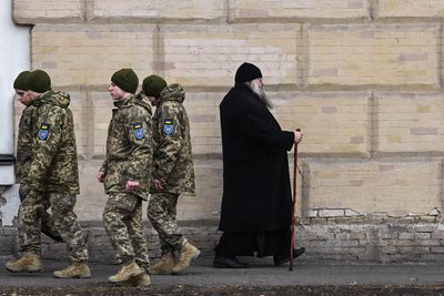 Курсанти проходять повз ченця на території Києво-Печерської Лаври у Києві, 14 березня 2023 року