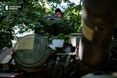 Танкіст на прихованих позиціях на сході слухає по рації обстановку на лінії зіткнення і паралельно спостерігає за роботою артилерії, червень 2022 року.