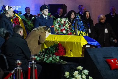 Родина підполковника поліції Михайла Павлушка біля труни з його тілом під час церемонії прощання із загиблими в авіакатастрофі у Броварах, Український дім, Київ, 21 січня 2023 року.