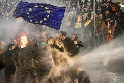 Протестувальники під водометом намагаються утримати прапор Євросоюзу під час зіткнень з поліцейськими біля грузинського парламенту в Тбілісі, 7 березня 2023 року Протестувальники під водометом намагаються утримати прапор Євросоюзу під час зіткнень з поліцейськими біля грузинського парламенту в Тбілісі, 7 березня 2023 року