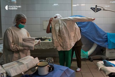 Медсестри одягають та готують хірурга до чергової операції, Київ, січень 2023 року. Нижній шар – важкий захисний свинцевий жилет, аби не отримати опромінення під час рентгену, зверху – стерильний халат та рукавички.