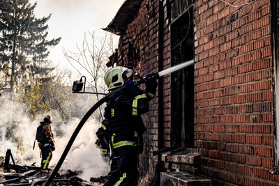 Рятувальник гасить пожежу в приватному будинку Рятувальник гасить пожежу в приватному будинку