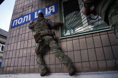 Український військовий заліплює синім скотчем російські літери "і" у слові "поліція" на стіні місцевого відділку у Лимані. До звільнення міста тут базувалися так звані правоохоронці з Росії та самопроголошеної "ДНР", Донеччина, жовтень 2022 року.