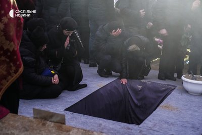 Рідні загиблого державного секретаря МВС Юрія Лубковича прощаються з них і, за християнською традицією поховання, кидають декілька жмень землі в яму з труною, Байкове кладовище, Київ, 21 січня 2023 року.