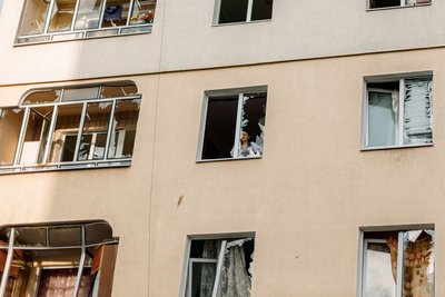 Жінка дивиться крізь пошкоджене вікно у Львові