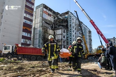 Рятувальники несуть загиблого через ракетний удар по будинку в Умані