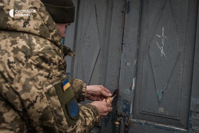 Пастор відчиняє замок на дверях покинулої хати, грудень 2022 року. Місцеві позначають "хрестиками" хати, у яких, на їх погляд, могли б жити військові під час реабілітації. Пастор відчиняє замок на дверях покинулої хати, грудень 2022 року. Місцеві позначають "хрестиками" хати, у яких, на їх погляд, могли б жити військові під час реабілітації.