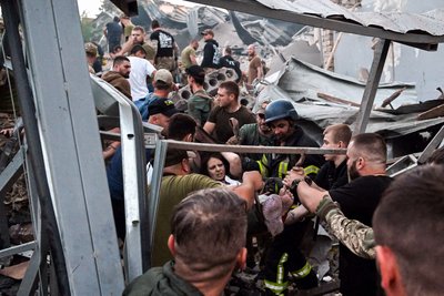 Рятувальники та волонтери виносять врятовану жінку з-під завалів у Краматорську