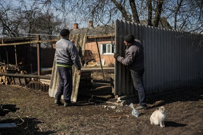 місцеві жителі лагодять паркан після російського обстрілу, Ворожба на Сумщині