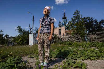 Жінка стоїть біля свого зруйнованого будинку у Богородичному