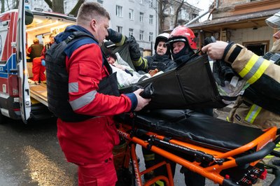 Медики та рятувальники заносять у швидку поранену жінку у Харкоку