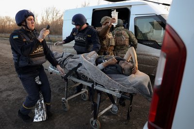Поліцейські передають співробітникам ДСНС пораненого в Авдіївці