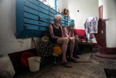Чоловік з дружиною сидять у коридорі житлового будинку у Херсоні